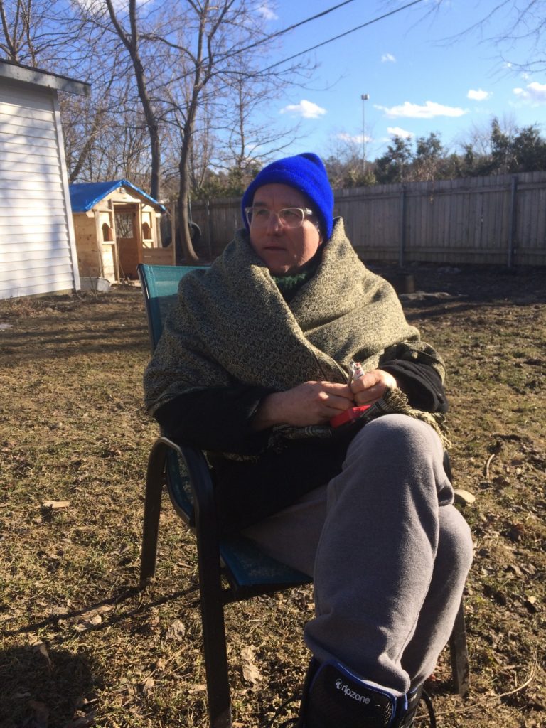 The poet RM Vaughan sitting in a lawn chair, bundled in a blanket. 